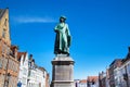 Statue of Jan Van Eyck and medieval house exterior against blue sky in Brugge, Belguim Royalty Free Stock Photo