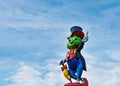 Statue of Jiminy Cricket under a cloudy blue sky.