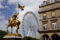 A statue of Joan of Arc stands in the Place des Victoires with a large ferris wheel in the Tuileries Gardens, Paris France - shot Royalty Free Stock Photo