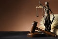 Statue of Lady Justice near gavel and open book on dark table, space for text. Symbol of fair treatment under law