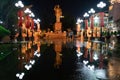 Statue of leader Ho Chi Minh at a main street with communist flags. Symmetrical reflection on the wet floor after the rain. People