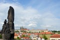 A statue looks from Charles Bridge towards Prague Castle. Royalty Free Stock Photo