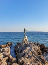 Statue of a maiden with seagull on rocky coast in Opatija, Croatia.