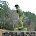 a statue of a man holding a baseball bat in a park