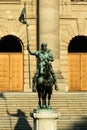 Statue of man on a horse holding flag by steps