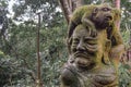 Statue of a monkey sitting on a human head covered by moss in the Sacret Monkey Forest in Ubud Bali Royalty Free Stock Photo