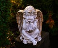 Statue of a peaceful angel child in the garden close-up. Stone cherub.