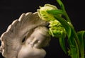 Statue of sad angel with tulip flowers as symbol of pain, fear and end of life. Remembrance concept Royalty Free Stock Photo