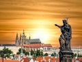 Statue of a saint on Charles Bridge pointing towards Prague Castel in Czech Republic. Beautiful sunset scene in Prague
