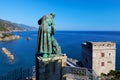 The statue of Saint Francis of Assisi caressing the wolf of Gubbio and Torre Aurora in Monterosso Al Mare, Cinque Terre, Italy.