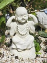 A statue of a small white monk, depicted in a pose of see no evil, hear no evil, speak no evil.