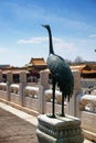 The statue of a stork inside the Palace Museum in Beijing, against marble columns and orange roofs, in a summer day with