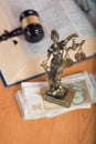 Statue of Themis on a pile of banknotes.
