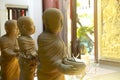 The statue of three monk novice carrying alms bowls decorated in a park at Thai temple and bright background.