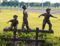 Statue of Three Young Boys Playing On A Wooden Fence