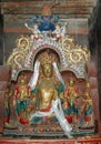 Statue of a Tibetan deity of golden color with a mythical blue bird in a monastery in Tibet