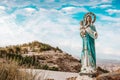 Statue of the virgin Mary in the mountains against the background of white clouds and blue sky, with a baby in her arms, patroness Royalty Free Stock Photo