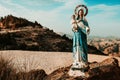 Statue of the virgin Mary in the mountains against the background of white clouds and blue sky, with a baby in her arms, patroness Royalty Free Stock Photo