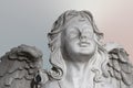 Statue of a white stone praying angel on pastel backgrouond, face and wings Royalty Free Stock Photo