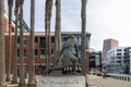 a statue of Willie Mays in front of Oracle Park with office buildings, restaurants and shops along the street and palm trees