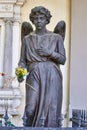 The statue of a young angel with flowers in his hand in the cemetery of S. Anna in Trieste