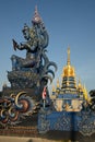 Statues of angels guarding in the style of applied Thai art in front of golden pagoda at Wat Rong Suea Ten temple. Royalty Free Stock Photo