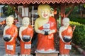 Statues of four smiling Buddhist monks holding alms containers w