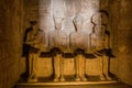 Statues of Ptah, Amun Ra, king Ramesses II and Ra-Horakhty illuminated by the rays of the sun in the Great Temple of Royalty Free Stock Photo