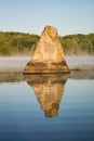 Statuesque Boulder Reflected In The Calm Early Morning Water