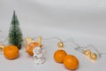 Statuette of an angel on a white background with a Christmas tree, tangerines and garlands