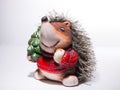 Statuette of a Hedgehog in Christmas red sweater with a Christmas tree