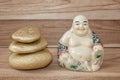 Statuette of laughing Buddha with stones, on a wooden background, Feng Shui.