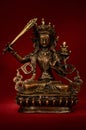 Statuette of Manjushri brandishing sword of wisdom on a red back