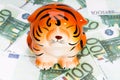 a statuette of a tiger against the background of one hundred euro bills. Symbol of the year and wealth