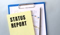 STATUS REPORT text written on notepad with pencil. Notepad on a folder with diagrams Royalty Free Stock Photo