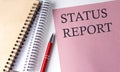 STATUS REPORT word on the pink paper with office tools on white background