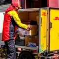 Local Worker Unloading And Delivering DHL Parcels Or Packages