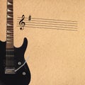 Stave and black electric rock guitar on the left side of rough cardboard background. Royalty Free Stock Photo