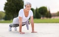 Positive elderly woman athlete headphones and sportswear doing push ups outside in city park