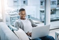 Stay connected even on the weekends. a handsome young man using his laptop while sitting on a sofa at home.