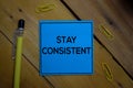 Stay Consistent write on a sticky note isolated on wooden background