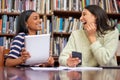 Stay consistent in your studying. two females using their devices in a library. Royalty Free Stock Photo