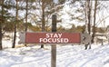 Stay focused symbol. Concept words Stay focused on beautiful wooden road sign. Beautiful forest snow blue sky background. Business Royalty Free Stock Photo