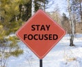 Stay focused symbol. Concept words Stay focused on beautiful red road sign. Beautiful forest snow blue sky background. Business, Royalty Free Stock Photo