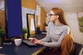 Stay home, a chic girl works in a homely atmosphere. Girl freelancer working at a computer with glasses