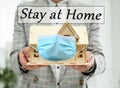 Stay at home during coronavirus quarantine. Woman holding house model with medical mask Royalty Free Stock Photo