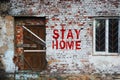 Stay home inscription on old brick wall .sealed door and barred window. Self-isolation at home from a coronovirus concept