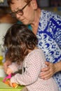 Real life. Morning meal cooking process. Little cute baby toddler girl with grandmother in the kitchen.