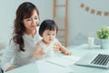 Stay at home mom working remotely on laptop while taking care of her baby Royalty Free Stock Photo
