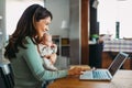 Stay at home mom working remotely on laptop while taking care of her baby. Royalty Free Stock Photo